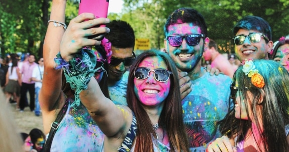 Group of people taking groufie with brightly coloured powder on their faces