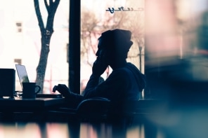 Silhouette of a person sitting at a table with a laptop